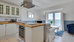 Une cuisine moderne avec des meubles blancs, un îlot central et une vue sur le balcon.