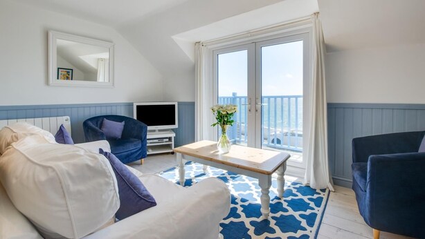 Un salon moderne comprenant un canapé, deux fauteuils, une table basse, un téléviseur à écran plat et un balcon avec vue.