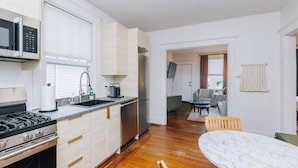 A modern kitchen with a stove, sink, and refrigerator. There is a dining area with a table and chairs. - Hyde Park 3BR Home with Fenced Backyard (Cincinnati)
