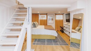 A bedroom with a bed, a desk, a chair, a mirror, and a staircase. - Hyde Park 3BR Home with Fenced Backyard (Cincinnati)