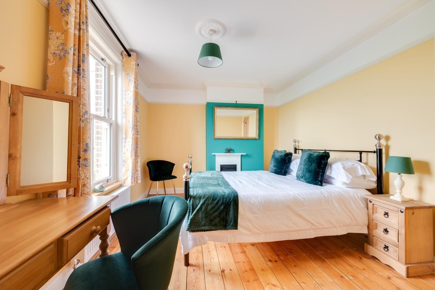 Une chambre à coucher comprenant un lit, un bureau, une chaise, une commode, un miroir et une cheminée.