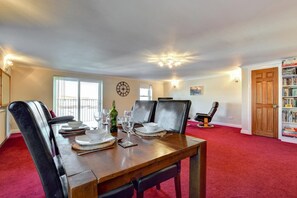 A dining room with a wooden table set for four, surrounded by leather chairs. A bookshelf and a door are visible in the background. - 2 Bed in Penzance (oc-mountv) (Penzance)