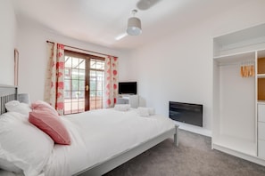 A bedroom with a bed, a TV, a wardrobe, and a window with curtains. - 2 Bed in Seahouses (oc-nb1974) (North Sunderland)