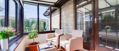 Ein sonnendurchfluteter Balkon mit Korbmöbeln, einem Topfpflanzen und Blick auf Grün.
