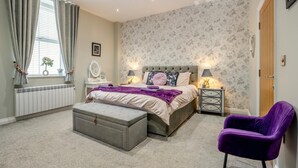 A bedroom with a bed, bedside tables, a chair, a radiator, and a window with curtains. - 2 Bed in Whitby (oc-c33513) (Whitby)