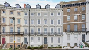 A row of townhouses with uniform window patterns, a central staircase, and a street in front. - 2 Bed in Whitby (oc-c33513) (Whitby)