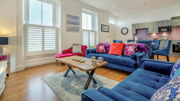 A modern living room with a blue sofa set, a wooden coffee table, and a red sofa. - 2 Bed in Whitby (oc-c33513) (Whitby)