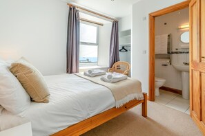 Une chambre à coucher comprenant un lit, une chaise, une vue sur la mer, ainsi qu’une salle de bain avec un lavabo et des toilettes.