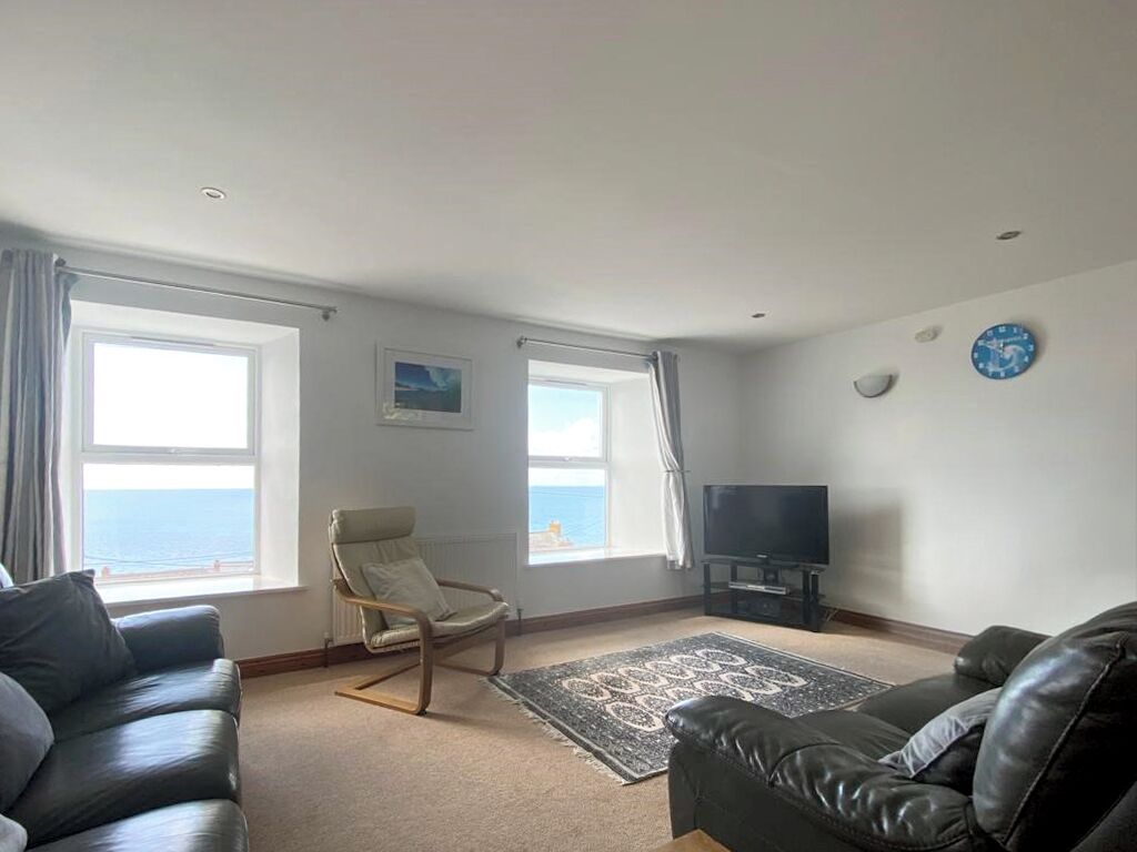A living room with two sofas, a chair, a television, and a rug.