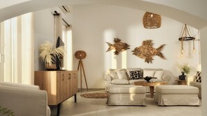 Ein modernes Wohnzimmer mit einer Couch, Poufs, einem Holzkabinett, Wanddekoration und einer Pendelleuchte.