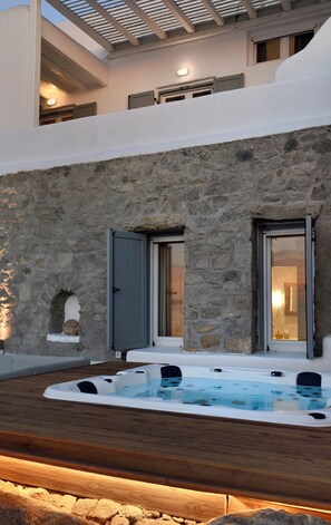 Ein modernes Haus mit Steinfassade, einem Whirlpool und einer Holzterrasse.