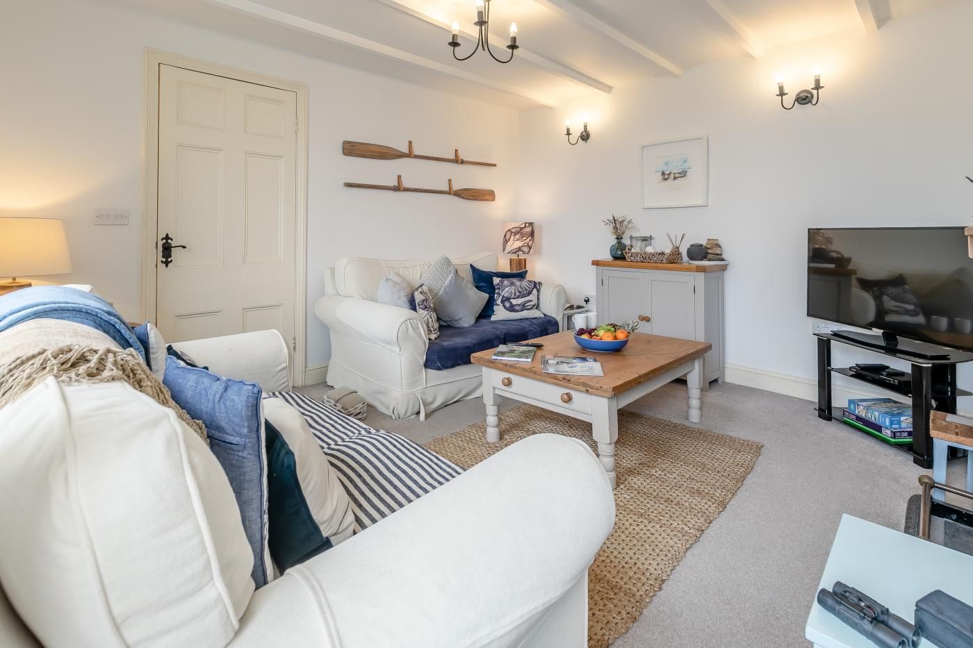 A living room with a white sofa, a coffee table, a television, and a bookshelf.