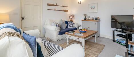 A living room with a white sofa, a coffee table, a television, and a bookshelf.