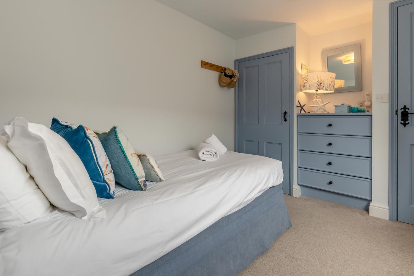 Een slaapkamer met een bed, een kaptafel, een deur en een spiegel aan de muur.