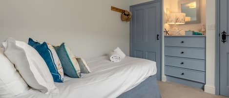 A bedroom with a bed, a dresser, a door, and a wall-mounted mirror.