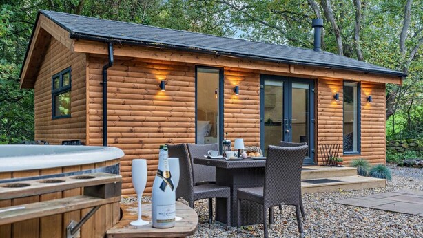 A log cabin with a hot tub, outdoor seating, and a stone wall. - 1 Bed in Littlebeck (oc-m33953) (Littlebeck)