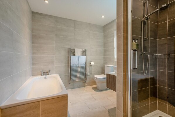 A modern bathroom with a bathtub, toilet, and shower area.