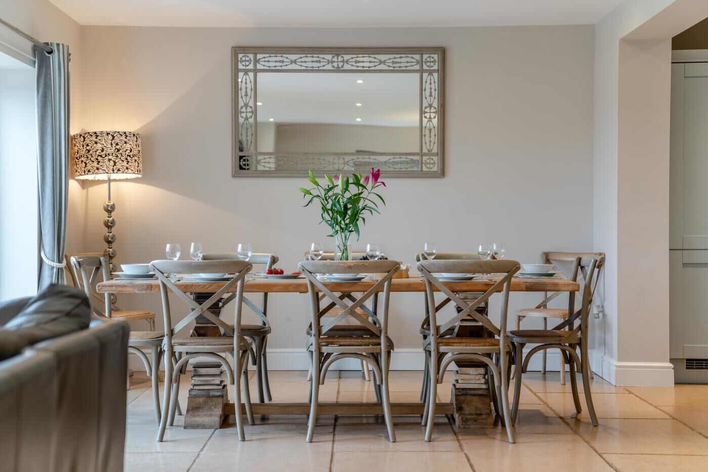 A dining area with a wooden table, six chairs, and a vase of flowers.