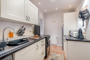 A modern kitchen with white cabinets, a black countertop, and a built-in oven. - 2 Bed in Aldborough (oc-2257) (Aldborough)