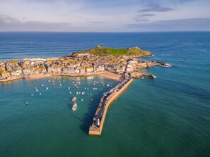 An aerial view of a coastal town with a harbor, boats, and a lighthouse. - 3 Bed in St. Ives (oc-marhou) (St Ives)