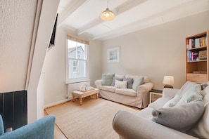 A cozy living room with a sofa, a coffee table, and a bookshelf. - 3 Bed in St. Ives (oc-marhou) (St Ives)