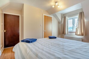 A bedroom with a bed, two doors, a window with curtains, and a ceiling light fixture. - 3 Bed in Marske (oc-o33522) (Marske)
