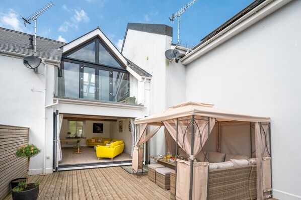 A modern house with a large glass bay window, a yellow sofa, and a covered outdoor seating area. - 4 Bed in Saundersfoot (oc-pw9262) (Saundersfoot)