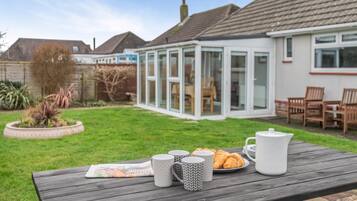 A patio with a table set for breakfast, including croissants and a newspaper.