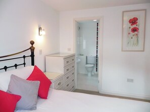 Une chambre à coucher avec un lit, une commode, une table de chevet et un tableau encadré au mur.
