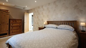 Une chambre à coucher avec un grand lit, une armoire en bois et une table de chevet avec une lampe.