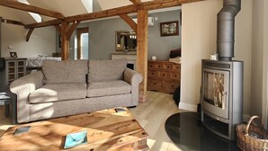 Un salon chaleureux avec un canapé, une table basse en bois et un poêle à bois.