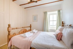 A bedroom with a wooden bed, a window with curtains, and a framed picture on the wall. - 3 Bed in Mousehole (oc-morcot) (Mousehole)