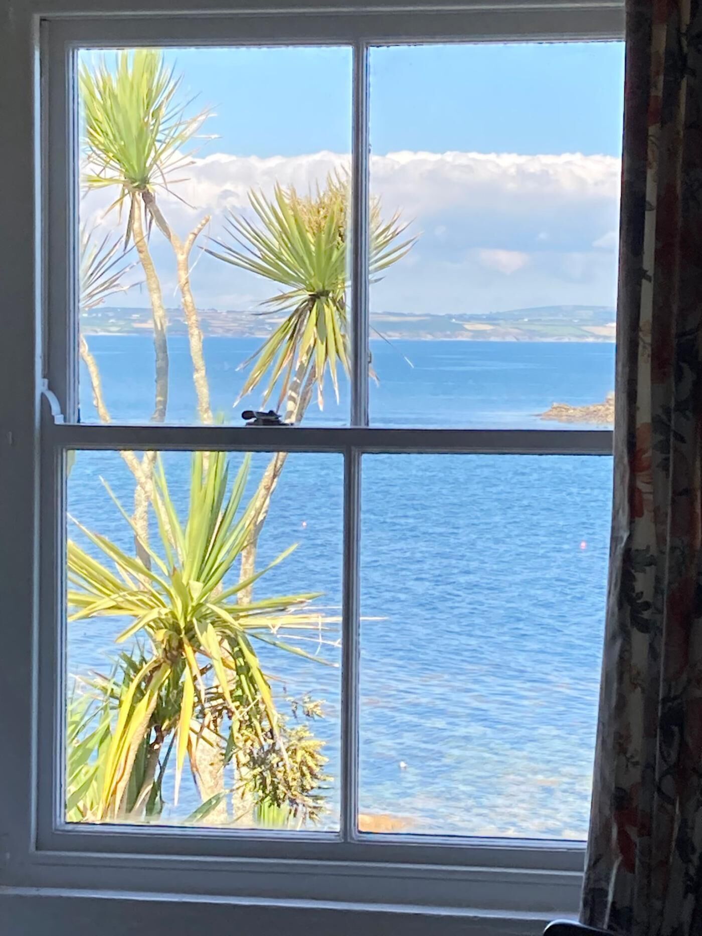 Une fenêtre donnant sur la mer et les palmiers.
