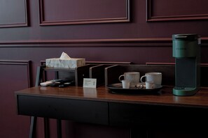 Ein dunkles Holztablett mit einer Keurig-Kaffeemaschine, einer Tablettgestellung für zwei Tassen, einer Taschentuchbox und einer Fernbedienung.
