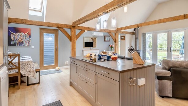 Een ruime keuken met houten balken, een eethoek met een tafel en stoelen, en uitzicht op de omgeving.
