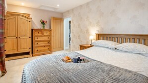 Een slaapkamer met een groot bed, een houten garderobe en een nachtkastje met een lamp.