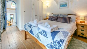 Een slaapkamer met een groot bed, een houten hoofdeinde, een sprei en uitzicht op een eetgedeelte.