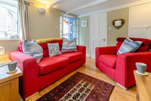 Un salon avec deux canapés rouges, un tapis à motifs et un plancher en bois.