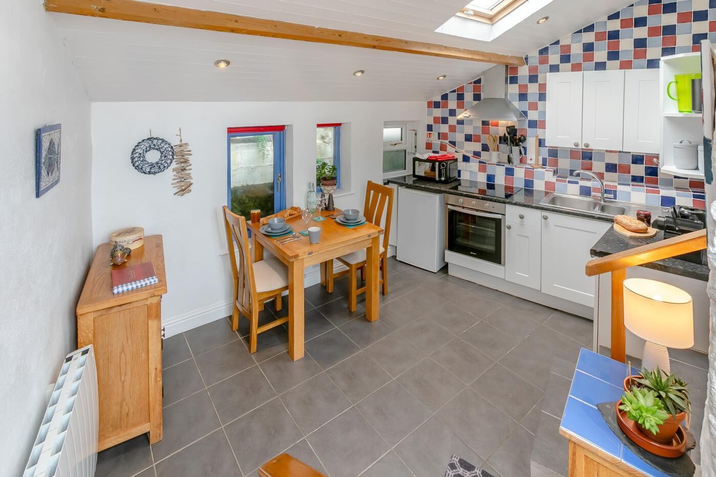 A modern kitchen with a dining area, featuring a tiled backsplash, wooden cabinets, and a built-in oven.