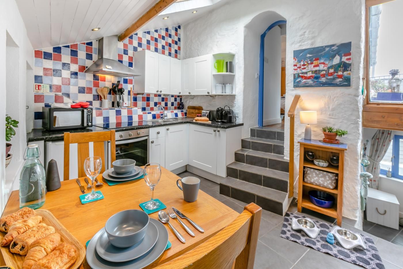 A compact kitchen with white cabinets, a microwave, and a checkered backsplash.