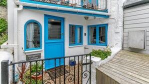 Een wit gebouw met blauwe accenten, een balkon en een houten terras.
