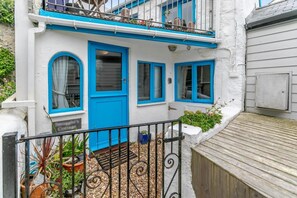 A white building with blue accents, a balcony, and a wooden deck. - 1 Bed in Porthleven (oc-smuggl) (Porthleven)