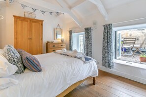 Ein Schlafzimmer mit einem hölzernen Bett, einem Schrank, einem Schminktisch, einem Spiegel und einem Fenster mit Vorhängen.