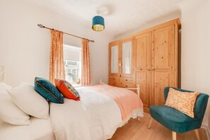 A bedroom with a bed, a chair, a wardrobe, and a window. - 3 Bed in Cromer (oc-2254) (Cromer)