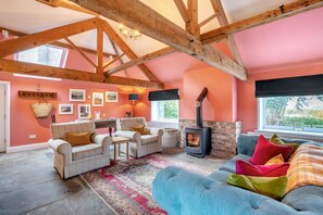 A spacious living room with a high ceiling, exposed wooden beams, a fireplace, and a large window. - 1 Bed in Crayke (oc-g33754) (Crayke)