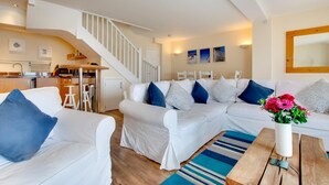A modern living room with a white sofa set, a wooden coffee table, and a blue-striped rug. A staircase leads to an upper level. - 2 Bed in Porthleven (oc-marin2) (Porthleven)