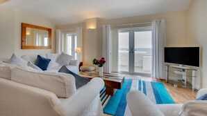A modern hotel room with a large bed, a sofa, a TV, and a balcony with a view of the sea. - 2 Bed in Porthleven (oc-marin2) (Porthleven)