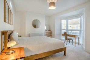 A bedroom with a large bed, a desk, a chair, a round mirror, and a window with blinds. - 3 Bed in Mumbles (oc-t34004) (The Mumbles)
