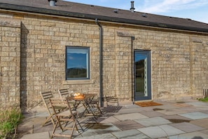 A stone building with a patio, a table with chairs, and a window. - 2 Bed in Dunsop Bridge (oc-w33524) (Dunsop Bridge)