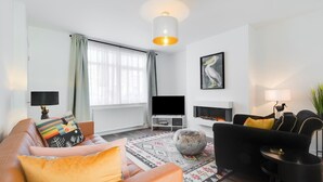 Ein modernes Wohnzimmer mit einer Couch, einem Couchtisch, einem Fernseher und einem Kamin.